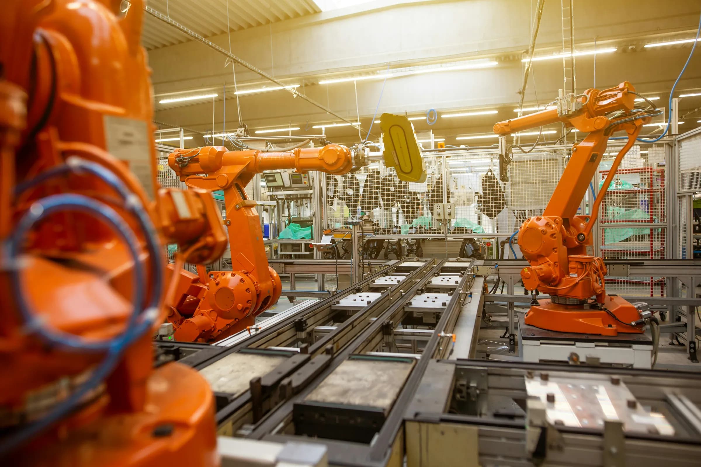 Orange industrial robots on a daylit production line